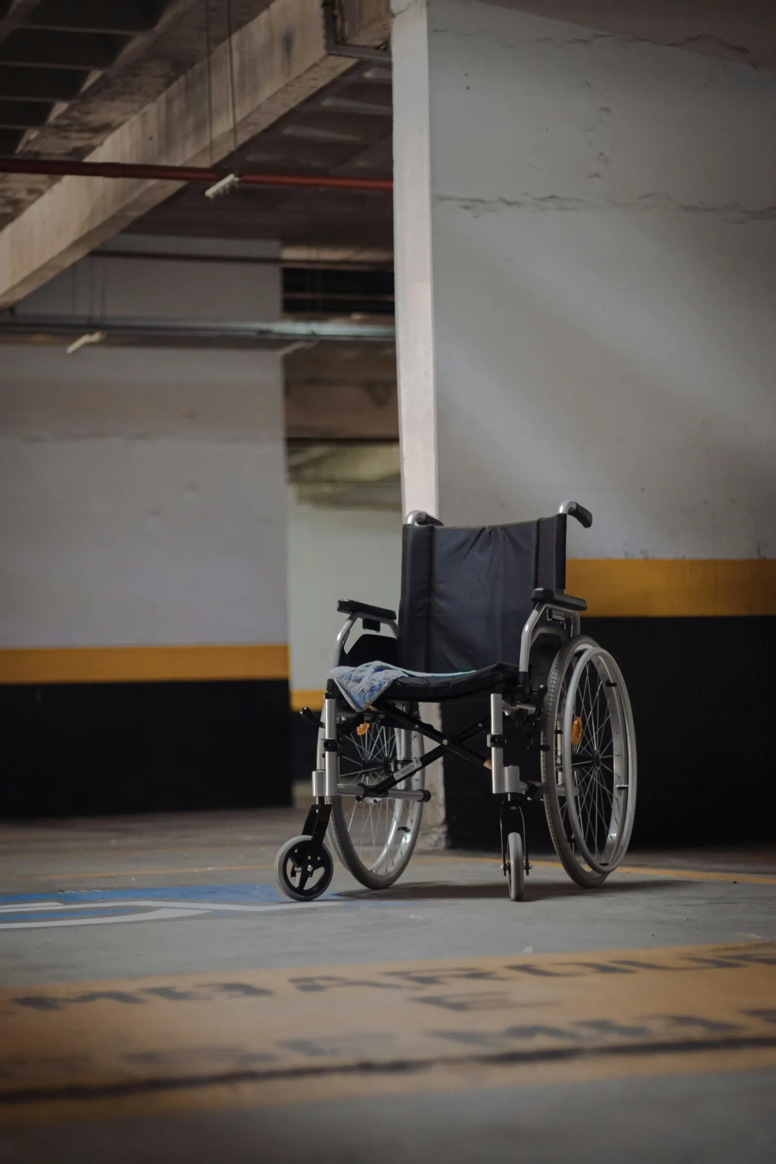 Empty wheelchair beside a marked accessible parking space in a covered garage