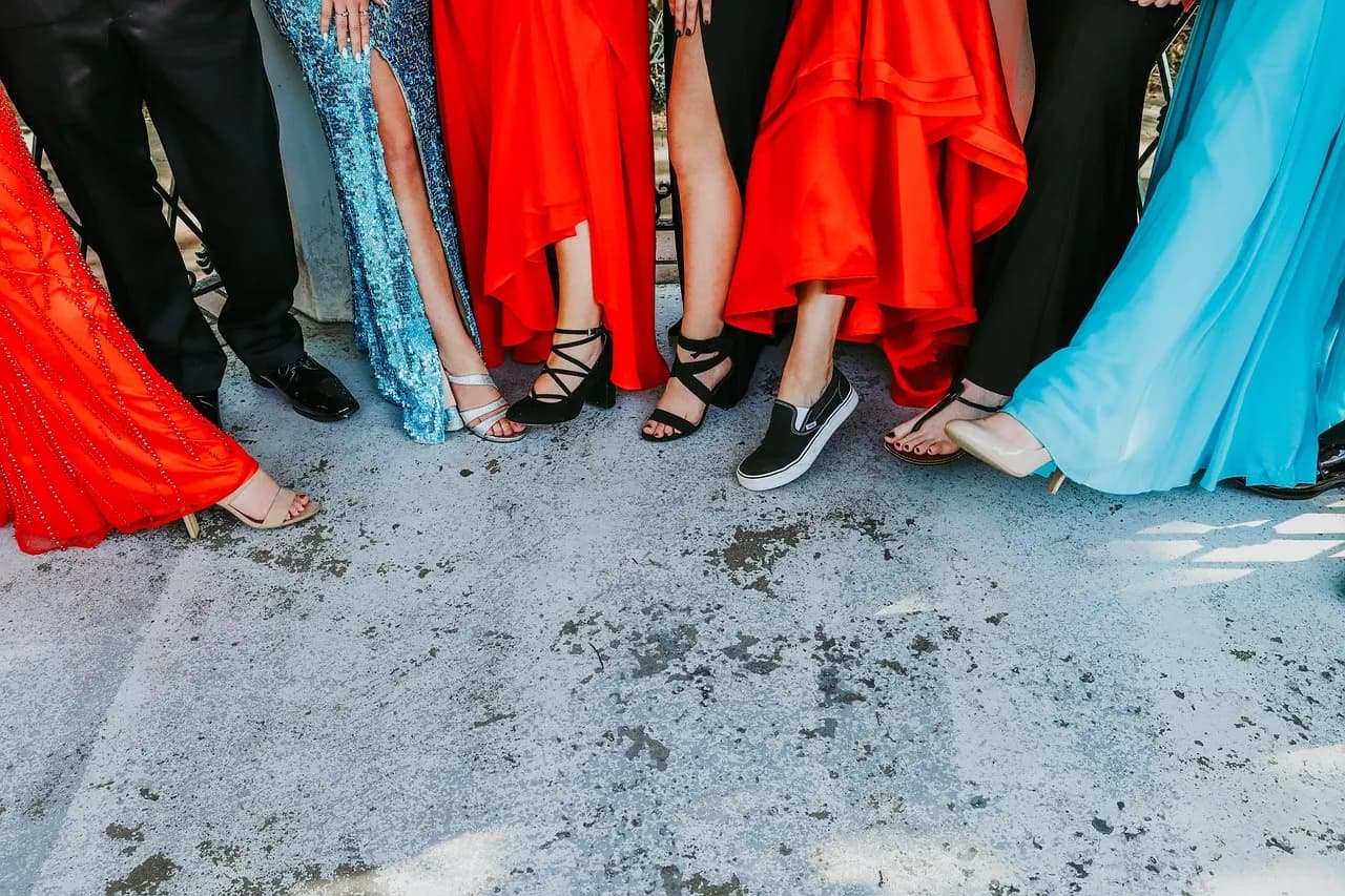 High school students in homecoming dresses and suits posing together before boarding their ride to the dance