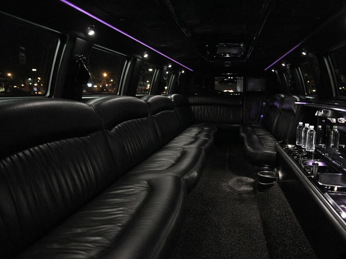 Stretch limousine interior with long black leather seating, a lit bar, and violet accent lights